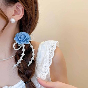 Detail of blue fabric rose hair clip with long hanging pearl chain tassels on model hair