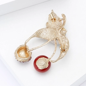 Detail view of the cherry brooch back with golden textured metal and secure safety pin