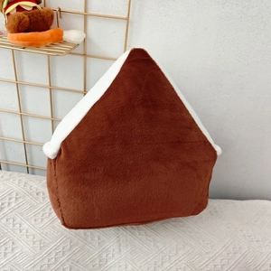Detail view of a house-shaped Christmas plush pillow with brown fur and white snow trim