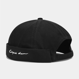Detail of black docker cap featuring white Carpe diem embroidery and adjustable strap back