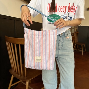 Détail de la texture d'un grand sac cabas rayé avec étiquette et bandoulière bleue