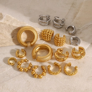 Collezione di ear cuff dorati e argentati con texture diverse su fondo di marmo