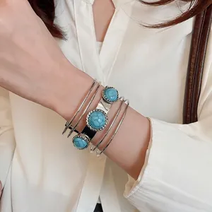 Multi-layer silver acrylic open bangle with blue turquoise stones on white background
