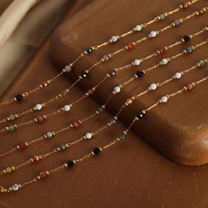 Handmade beaded necklace set with gold chain and colorful faceted stones on wood