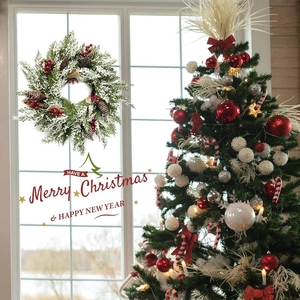 Couronne de Noël avec aiguilles enneigées, baies rouges et pommes de pin sur fenêtre