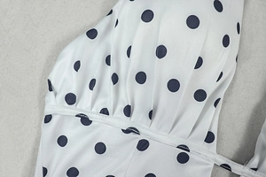 Detailed close-up of white polka dot fabric with high-quality flat stitching and texture