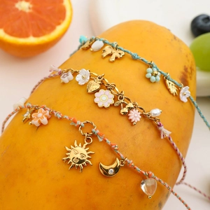 Braided cord bracelets with gold charms displayed on fresh papaya fruit setup