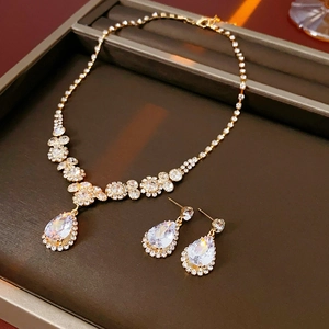Détail du collier à fleurs dorées et des boucles d'oreilles en zircon en forme de goutte