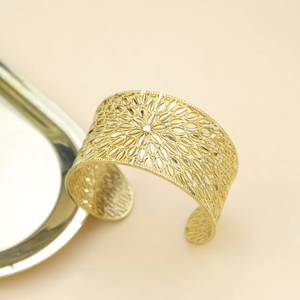 Exquisite hollow floral wide open bangle in gold finish on a minimal metallic plate