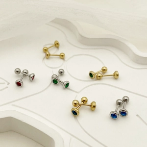 Detailed macro view of colorful zircon dumbbell earrings on a minimalist white tray