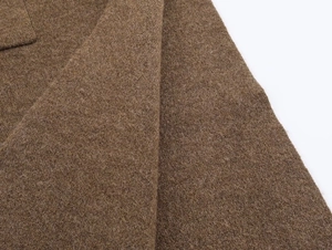 Macro shot of dark brown wool knit fabric showing premium texture and neat stitching details