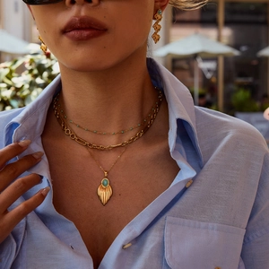 Close-up of gold layered necklace and matching drop earrings with turquoise stones