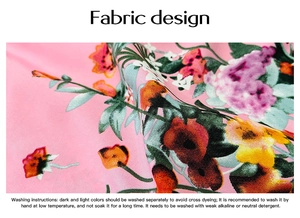 Detailed macro view of pink floral fabric with colorful flower prints and care instructions