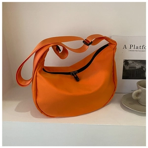 Close-up of bright orange nylon crescent bag with adjustable strap and black zipper detail