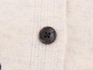 Close-up of fluffy knit cardigan fabric with a textured dark brown round button