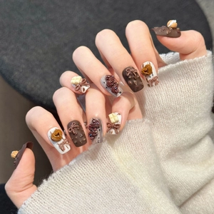 3D dessert-themed press-on nails with chocolate bows and pastries on a warm background