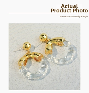 Detail of artistic gold and clear glass round hoop earrings with modern twisted design