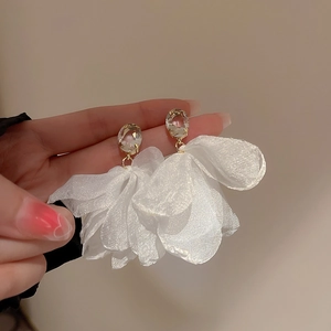 Close-up detail of elegant white fabric flower earrings featuring a shimmering crystal stud