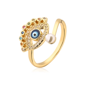 Close-up of gold plated evil eye ring with blue enamel, colorful zircons and pearl detail