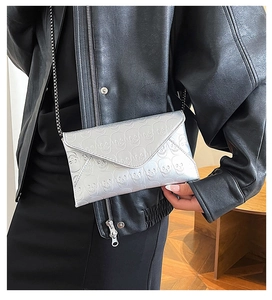 Close-up of silver envelope bag featuring skull embossing and metallic chain strap