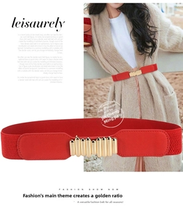 Detail of red elastic waist belt with gold wave metal buckle and leather texture ends
