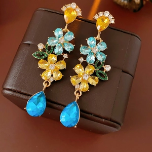 Detailed close-up of vintage flower earrings with colorful gems and blue teardrop pendants