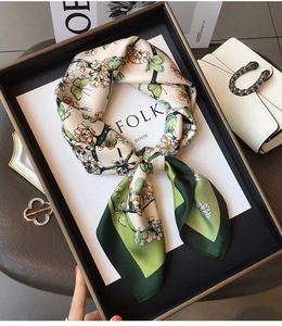 Close-up of a floral silk scarf with butterfly prints and green borders on a tray