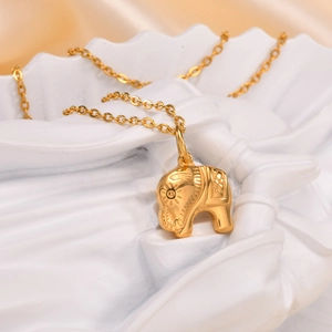 Detailed macro view of a gold elephant pendant necklace featuring sunburst engravings
