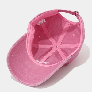 Detail of pink washed cotton baseball cap showing internal six-panel stitching and adjustable buckle