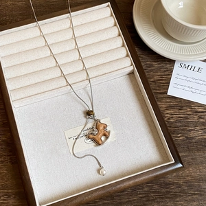 Detailed view of silver snake chain necklace with wooden horse pendant and pearl accent