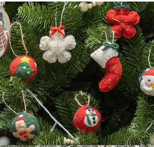 Detail view of wool felt Christmas ornaments like snowflakes and socks on tree branches