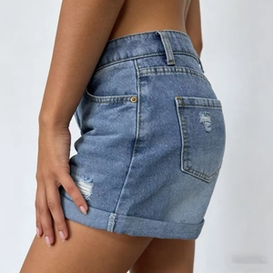Dettaglio degli shorts in denim a vita alta con orli sfrangiati e trama consumata