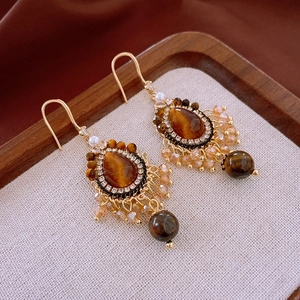 Détail de boucles d'oreilles vintage en or avec oeil de tigre ambré et perles champagne