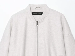 Detailed close-up of light grey bomber jacket with ribbed collar and metal zipper