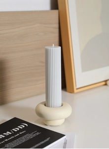 Close-up of minimalist cream ceramic candle holder with a white ribbed pillar candle