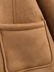 Detailed macro view of the brown suede fabric texture and stitching on the jacket pocket