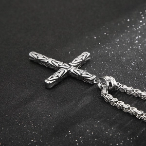 Macro side view of silver cross pendant with intricate Byzantine chain texture