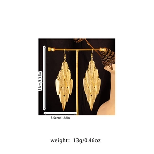 Close-up of golden layered leaf earrings with size measurements on a metal display stand