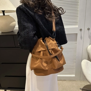 Gros plan d'un sac seau marron à cordon porté par un mannequin dans un cadre intérieur