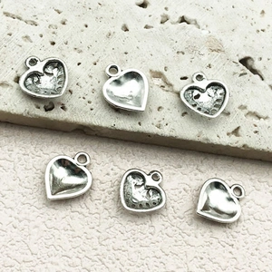 Detail of vintage silver alloy heart pendants showing front and back textures for DIY jewelry