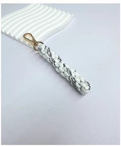 Detailed macro view of black and white woven cord with golden metal lobster clasp