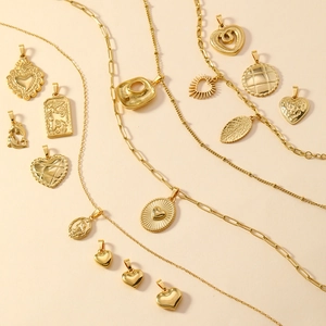 Detailed assortment of gold heart and oval pendants with mixed chains on beige background