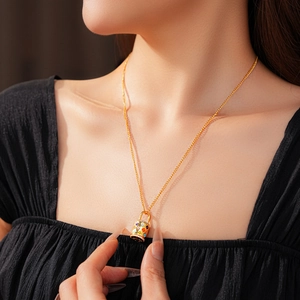 Close-up of a gold lock pendant necklace with colorful floral patterns on a model