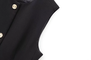 Détail de l'épaule d'un gilet noir et texture de la boucle ronde en métal doré