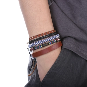 Détail de l'ensemble de cinq bracelets multicouches en cuir tressé portés au poignet masculin