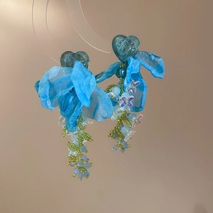 Detail of blue organza flower earrings with heart beads and beaded tassels in a macro view