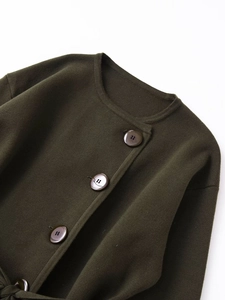 Détail d'un cardigan en maille vert olive avec de gros boutons et un tissu épais texturé