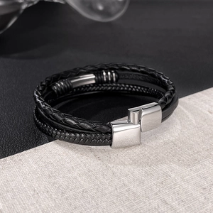 Detailed macro view of black multi-layer braided leather bracelet with silver metal clasp