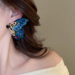Detailed shot of large butterfly earring with blue velvet and colorful rhinestones