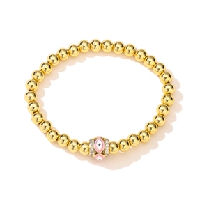 Macro shot of 18K gold-plated beaded bracelet with pink evil eye charm and zircons